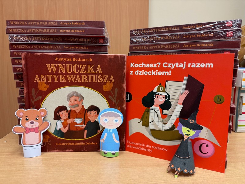 Książki ułożone w stosik, przed nimi książka zwrócona okładką, na której widać dziadka oraz wnuczęta. Obok postacie wycięte z kartki: babcia, czarownica i miś.