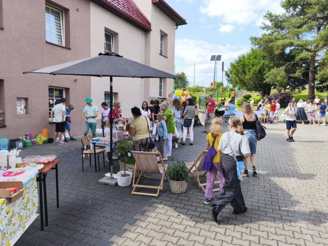 Uczniowie i społeczność lokalna na placu szkolnym podczas rodzinnego festynu.