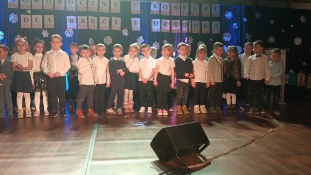 Dzieci w odświętnych strojach śpiewają dla babci i dziadka.